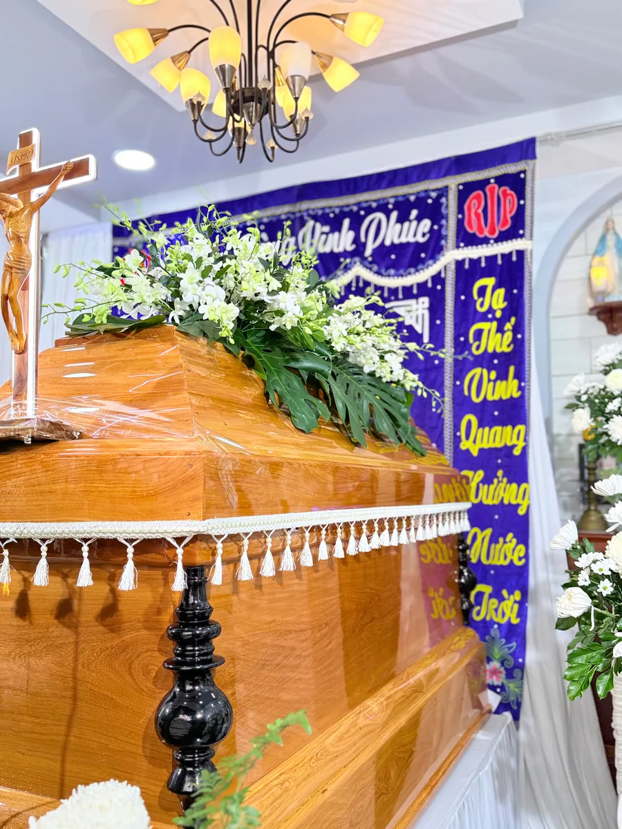 Áo quan gỗ, thánh giá và hoa trắng trong không gian tang lễ Công Giáo