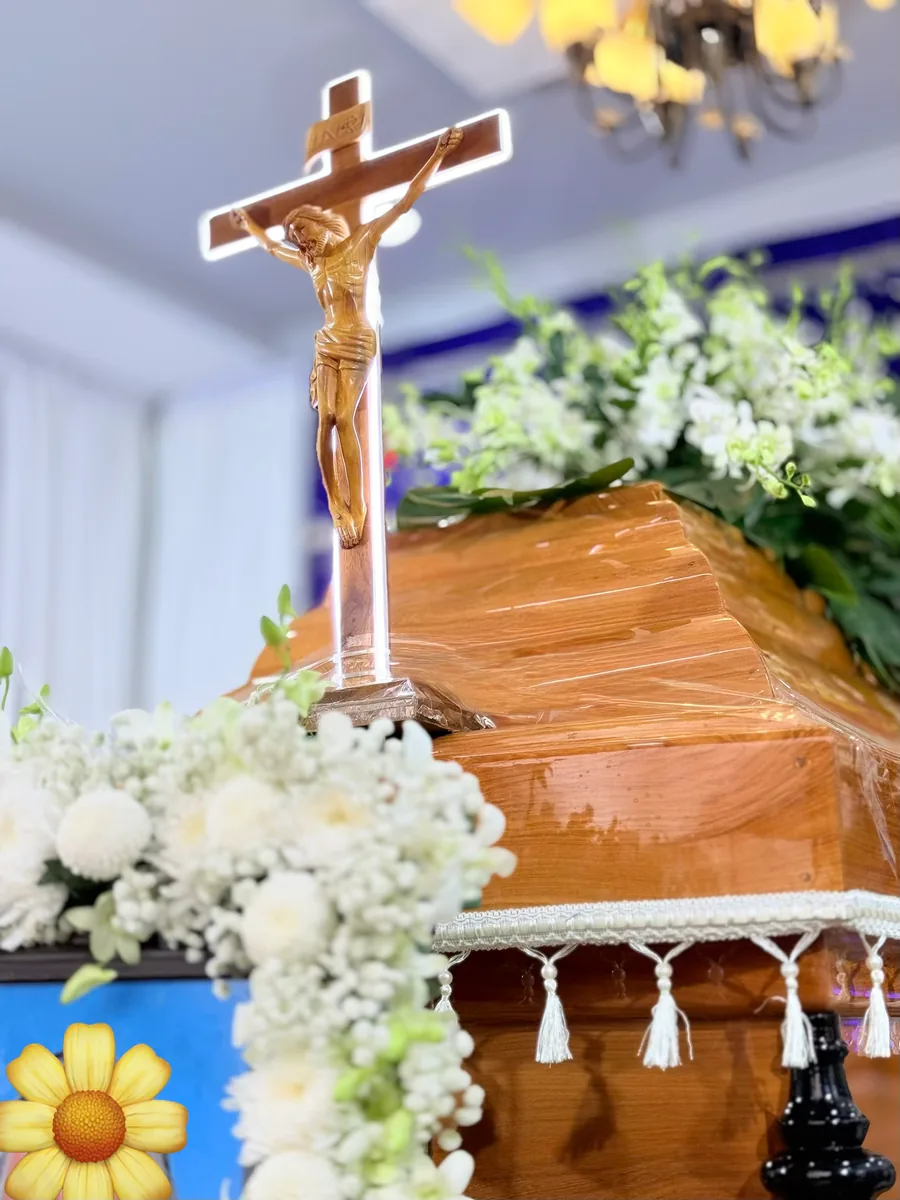 Thánh giá đặt trên áo quan gỗ và hoa trắng