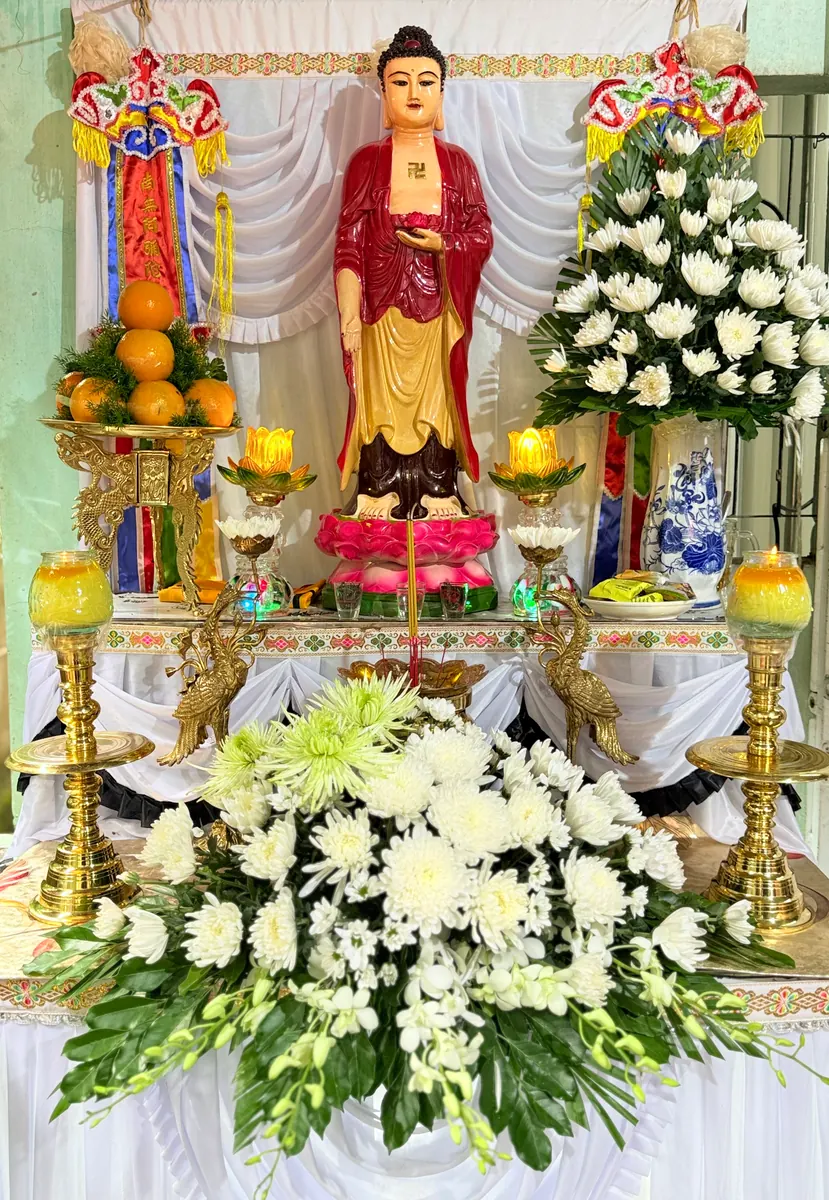 Tượng Phật áo đỏ cùng hoa cúc, hương và đèn